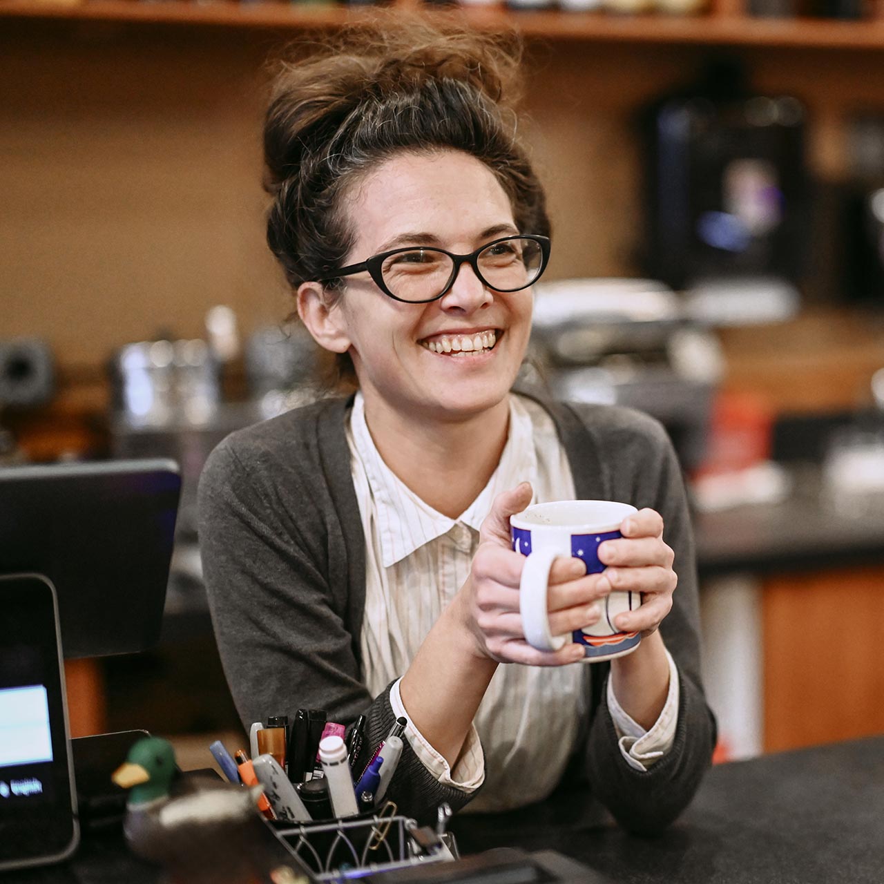 Woman holding a coffee cup while standing at the counter